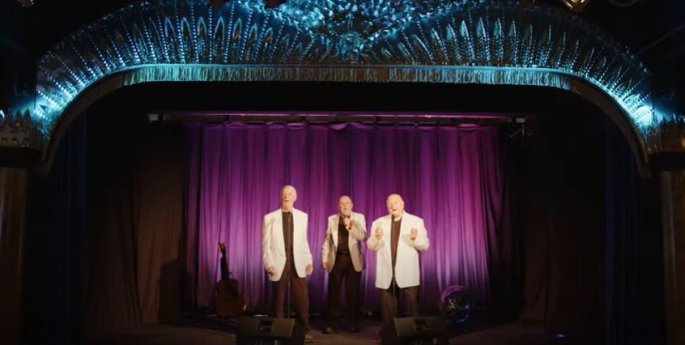 Three older males singing on the Divine Theater stage